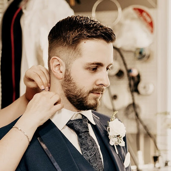 Image of a man in a suit having collar adjusted