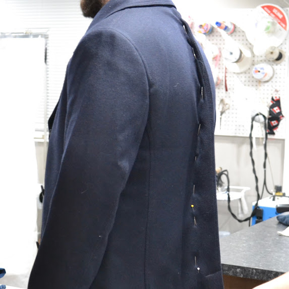Image of a mans upper body wearing a suit jacket with the back spine pinned up